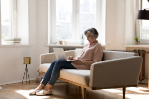 Middle aged grey haired freelance woman using laptop at home